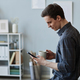 Side view smiling young man using smartphone in office at coffee break - PhotoDune Item for Sale