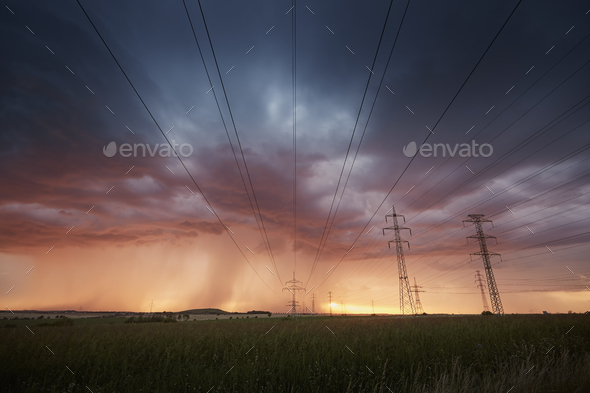 Landscape with electricity pylons under dramatic clouds of approaching storm - Stock Photo - Images