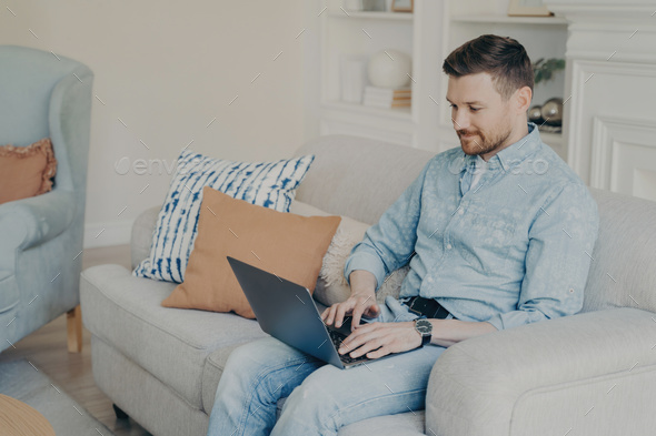 Young businessman working from home while sitting on couch - Stock Photo - Images