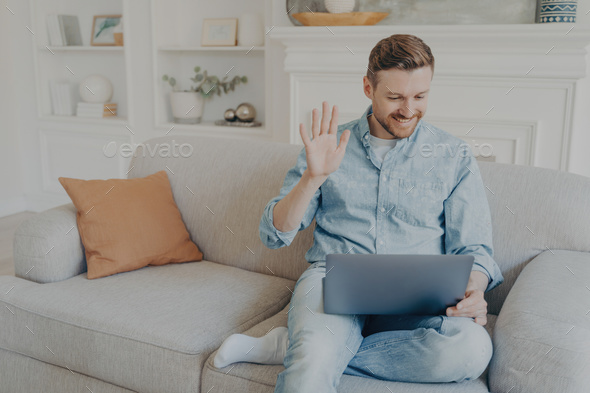 Young man speaking with family using notebook while sitting on couch - Stock Photo - Images