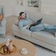 Young businessman working remotely at home while lying on couch - PhotoDune Item for Sale