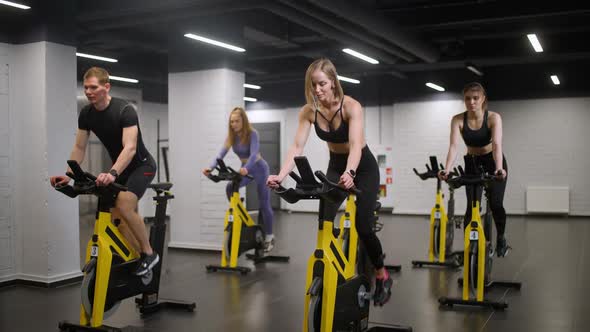 Group of People is Training on a Spin Bikes Performs Aerobic Endurance Training on the Simulators in alt