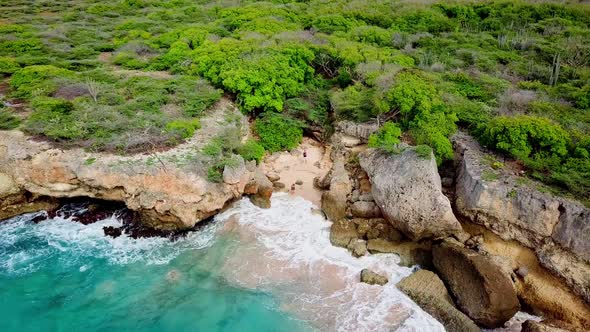 Dolly out aerial view of a couple on a hidden beach in Westpunt, Curacao, Dutch Caribbean island alt