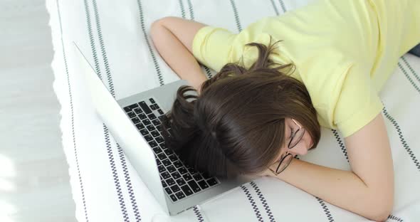 Young Beautiful Woman Fell Asleep on the Bed Her Head is on the Laptop Keyboard