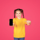 Cute Preteen Girl Pointing At Smartphone With Blank Screen In Hand - PhotoDune Item for Sale