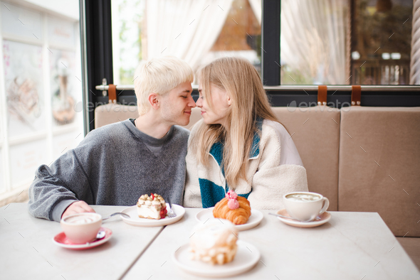 Smiling love couple of teen girl and boy spend time together in coffee house - Stock Photo - Images