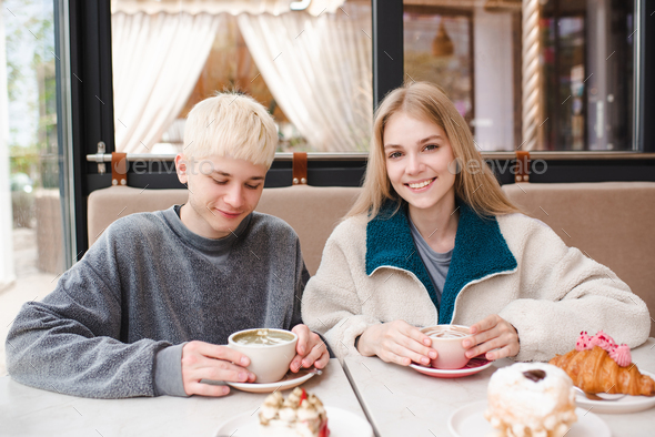 Smiling love couple of teen girl and boy spend time together in coffee house - Stock Photo - Images
