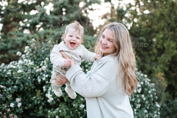 Happy mother holding newborn baby outdoor over flowers - Stock Photo - Images