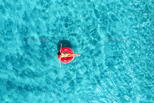 Aerial view of a woman swimming with red swim ring in blue sea - Stock Photo - Images