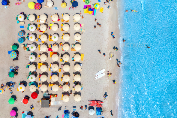 Aerial view of colorful umbrellas on beach, people in blue sea - Stock Photo - Images