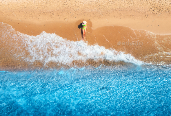 Aerial view of woman on sandy beach and blue sea with waves - Stock Photo - Images
