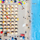 Aerial view of colorful umbrellas on beach, people in blue sea - PhotoDune Item for Sale