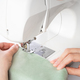 Female hands stitching white fabric on modern sewing machine at workplace in atelier - PhotoDune Item for Sale