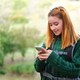 Happy redhead young female hiker consulting smartphone while trekking. - PhotoDune Item for Sale