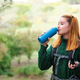 Hiker redhead woman drinking water from bottle wearing a backpack. - PhotoDune Item for Sale