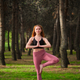 Redhead young woman doing tree yoga pose in a forest. - PhotoDune Item for Sale