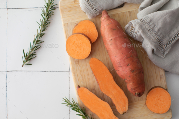Raw sweet potatoes on cutting board. . Orange kumara, yam. Healthy eating. - Stock Photo - Images