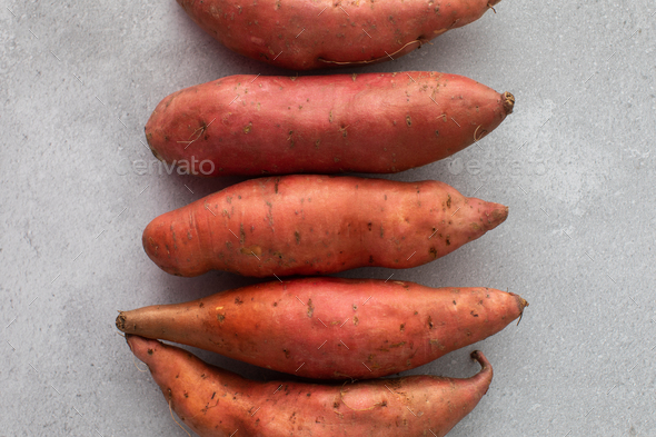 Raw sweet potatoes on a grey background. Orange kumara, yam. Healthy eating. - Stock Photo - Images