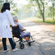 Doctor help and care Asian senior woman patient sitting on wheelchair at park. - PhotoDune Item for Sale