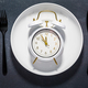White plate and clock on a dark background with copy space.  - PhotoDune Item for Sale