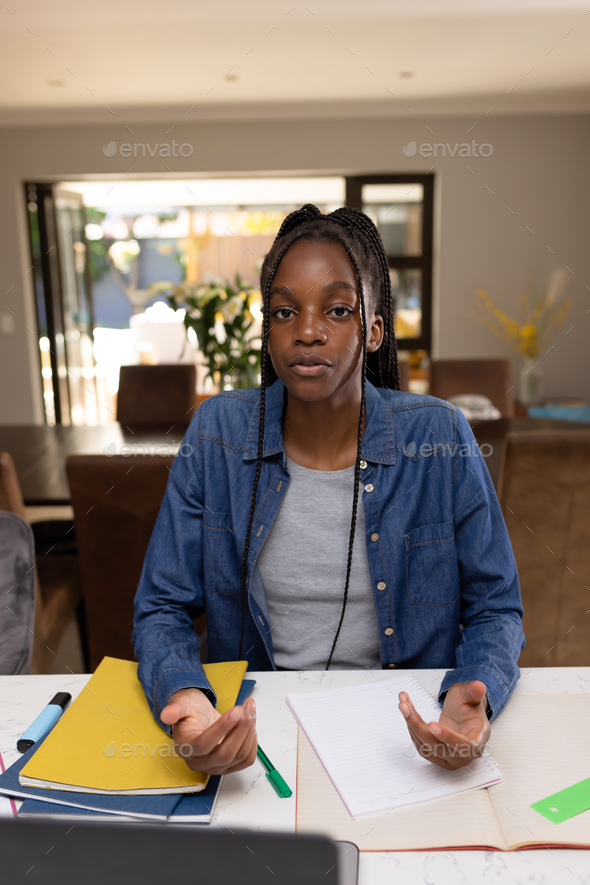African american teenager girl sitting at table and having video call - Stock Photo - Images