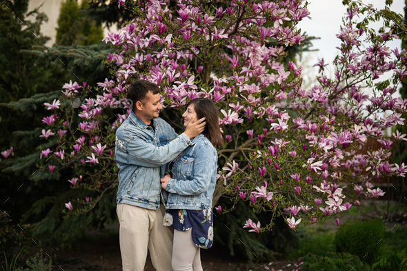 Tender couple in love wear jeans jacket enjoying nice spring day near magnolia blooming tree. - Stock Photo - Images