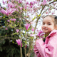 Preschooler girl in pink jacket enjoying nice spring day near magnolia blooming tree.  - PhotoDune Item for Sale