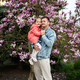Father with daughter in hands enjoying nice spring day near magnolia blooming tree. - PhotoDune Item for Sale