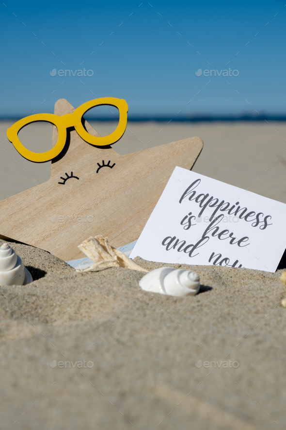 HAPPINESS IS HERE AND NOW text on paper greeting card on background of funny starfish in glasses