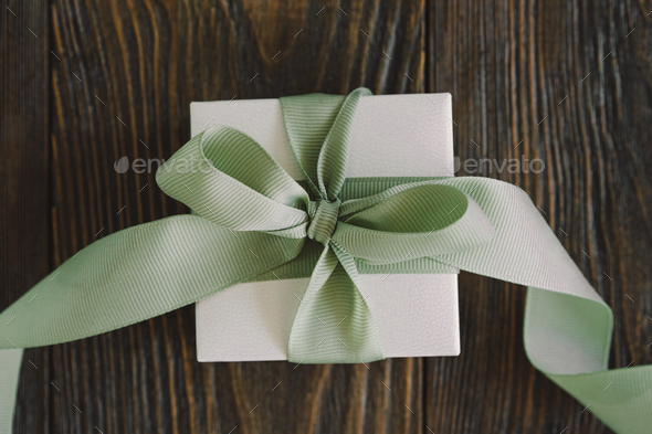 Gift or present box with green ribbon on wood background - Stock Photo - Images