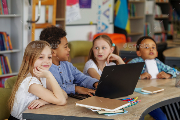 Multiracial group of children sitting in row at school classroom and using laptops. Back to school. - Stock Photo - Images