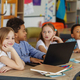 Multiracial group of children sitting in row at school classroom and using laptops. Back to school. - PhotoDune Item for Sale