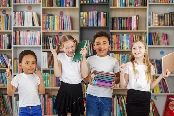 Four children holding stack of books in library. Multiethnic classmates having fun. Back to school. - Stock Photo - Images