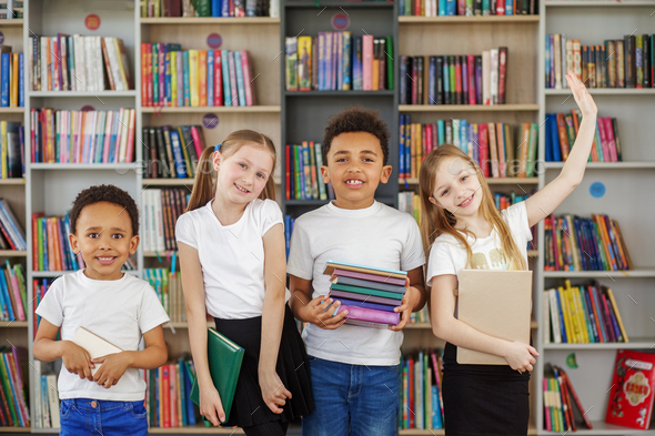Four children holding stack of books in library. Multiethnic classmates having fun. Back to school. - Stock Photo - Images