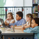 Multiracial group of children sitting in row at school classroom and using laptops. Back to school. - PhotoDune Item for Sale