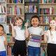 Four children holding stack of books in library. Multiethnic classmates having fun. Back to school. - PhotoDune Item for Sale