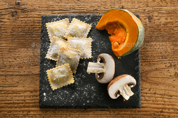 Raw ravioli with pumpkin and mushrooms on black board - Stock Photo - Images
