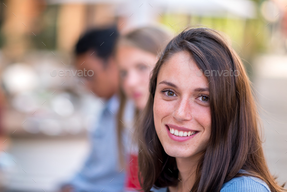 Smiling young woman sitting and looking at camera - Stock Photo - Images