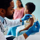 Black pediatrician giving vaccine to a child at doctor&#39;s office. - PhotoDune Item for Sale