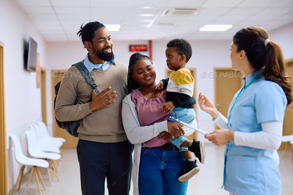 Happy black family talking to a nurse in hallway at doctor's office. - Stock Photo - Images