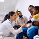 Female pediatrician talking to black little boy who is sitting on mother&#39;s lap at the clinic. - PhotoDune Item for Sale