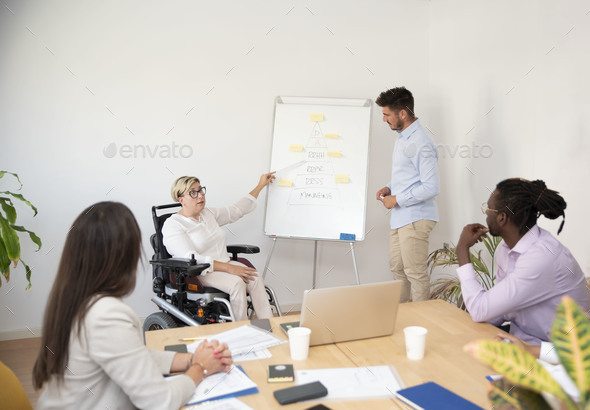 a businesswoman in the wheelchair with a disability leading a company meeting