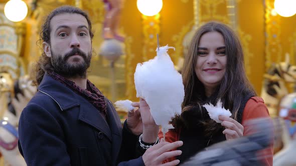 Happy carefree lovers eating cotton candy, smiling at camera-outdoor alt