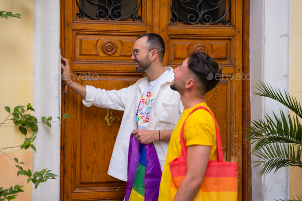 Lgbt concept, gay male couple shaking friends to go to pride party with rainbow flag
