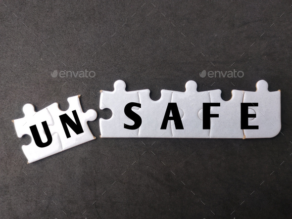 White puzzle with text UN SAFE on black background. - Stock Photo - Images