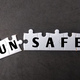 White puzzle with text UN SAFE on black background. - PhotoDune Item for Sale