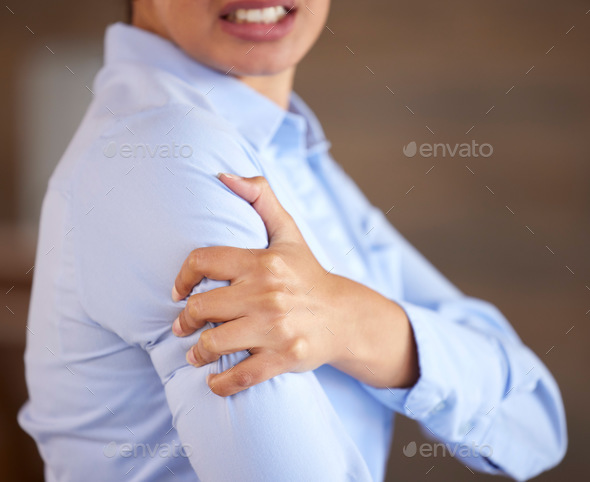 Closeup of unknown mixed race businesswoman standing alone and suffering from sore shoulder or arm