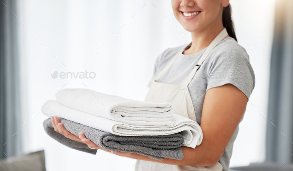 Hands of a woman holding a pile of laundry. Woman holding a stack of neat, folded laundry. Woman cl