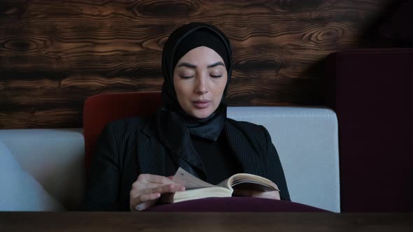 Young Muslim Woman in Hijab Reading a Book