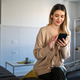 Young woman wearing sweater using smartphone at home, communication and social network concept, - PhotoDune Item for Sale